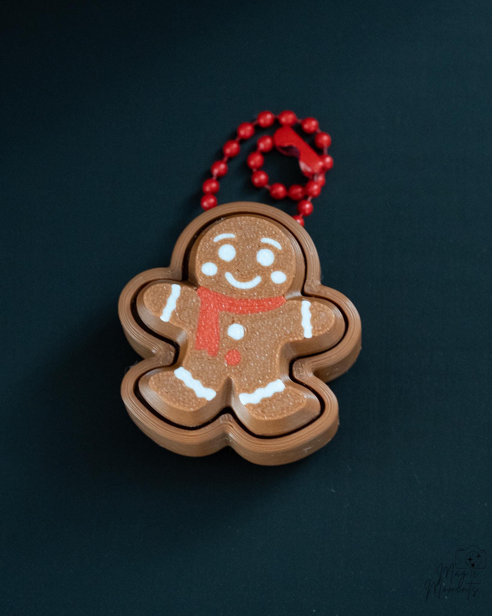 Mini gingerbread clicker with red hanging loop and cartoon style face