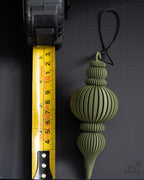 olive green ornament next to measuring tape for scale