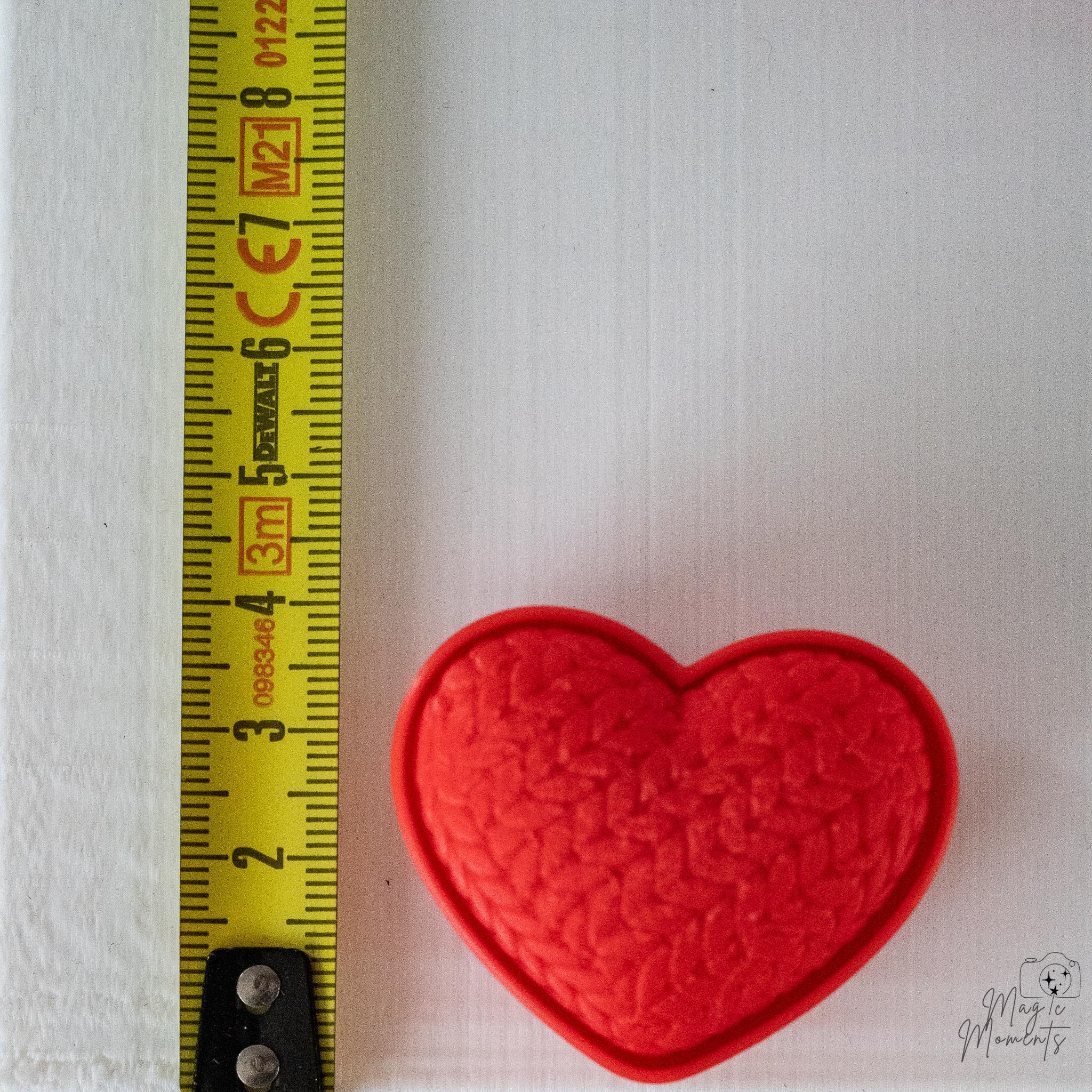 Heart clicker next to measuring tape for scale