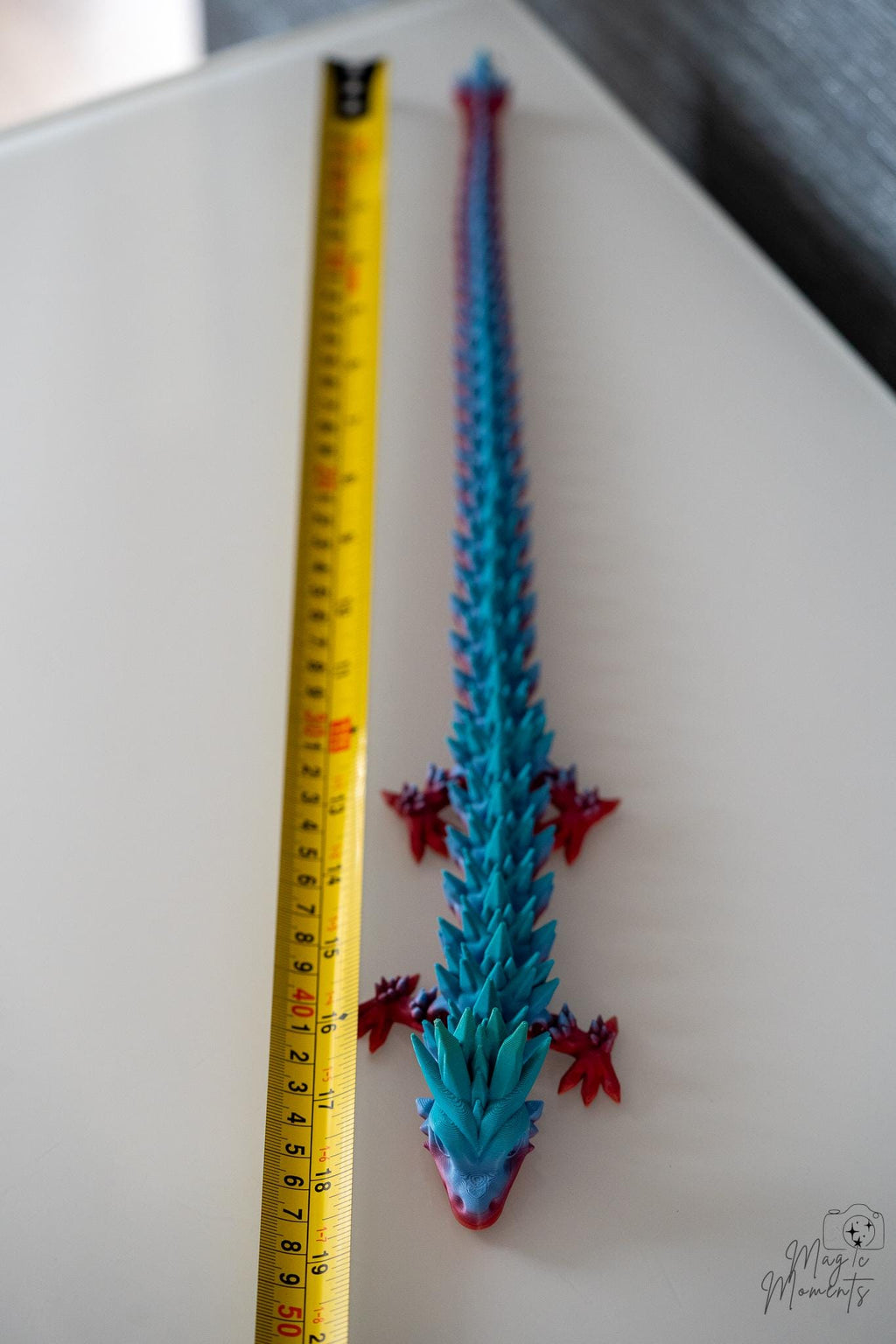 Articulated dragon next to measuring tape for scale