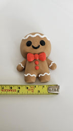 Small gingerbread man Christmas decoration next to measuring tape for scale