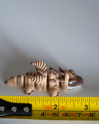 skeleton dinosaur figure next to measuring tape for scale