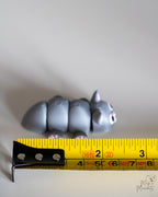 grey cat miniature figurine next to measuring tape for scale