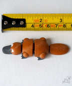 platypus figurine next to measuring tape for scale
