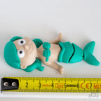 mermaid figurine next to measuring tape for scale