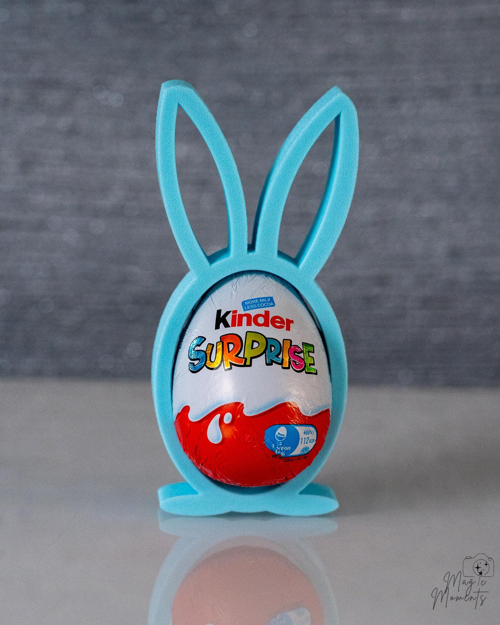 Kinder Surprise egg in a blue bunny holder on a gray background