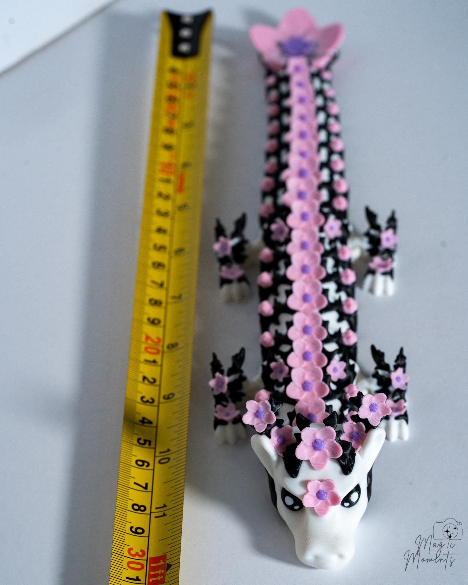 Articulated floral dragon next to measuring tape for scale