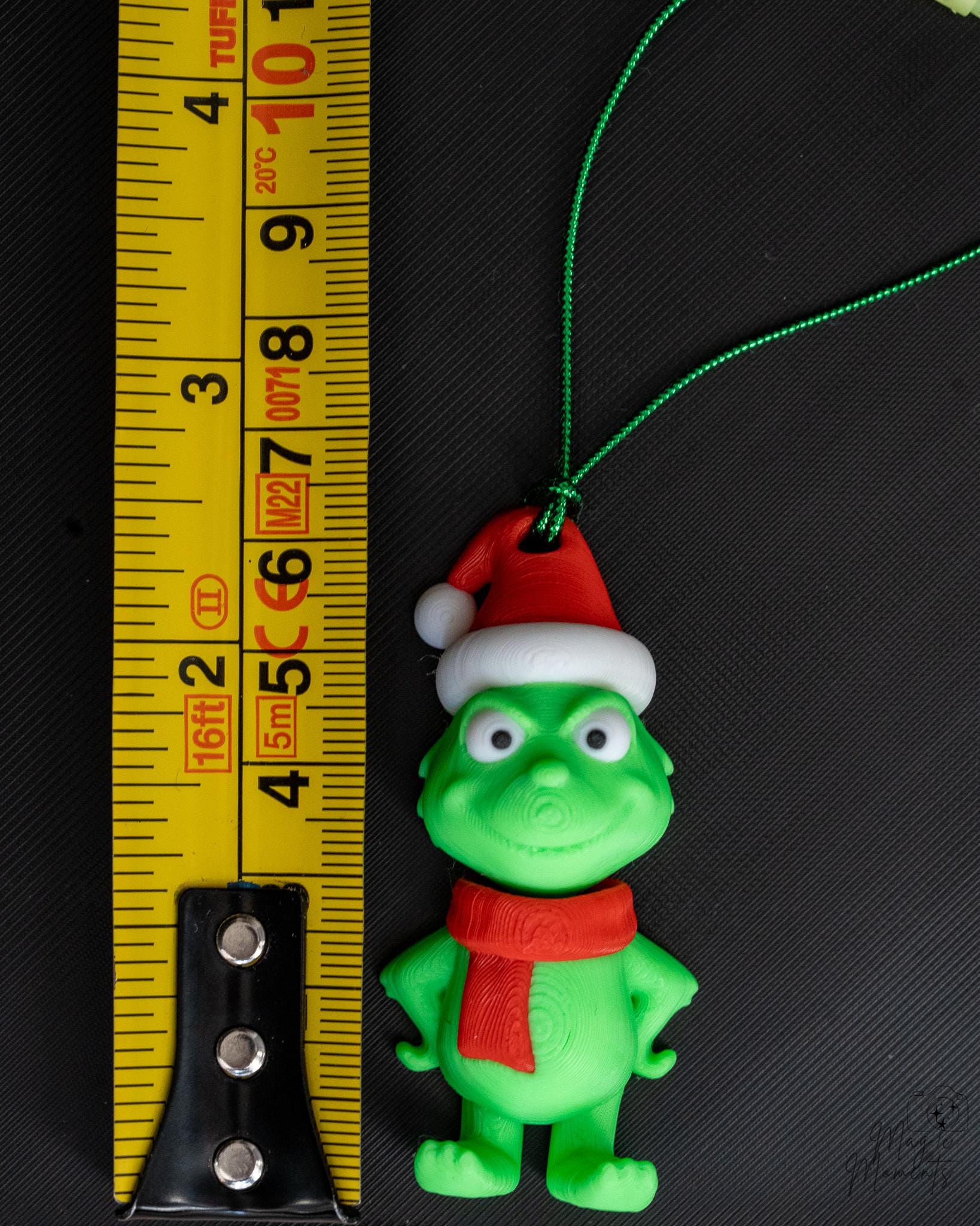 green christmas character Christmas ornament next to measuring tape for scale