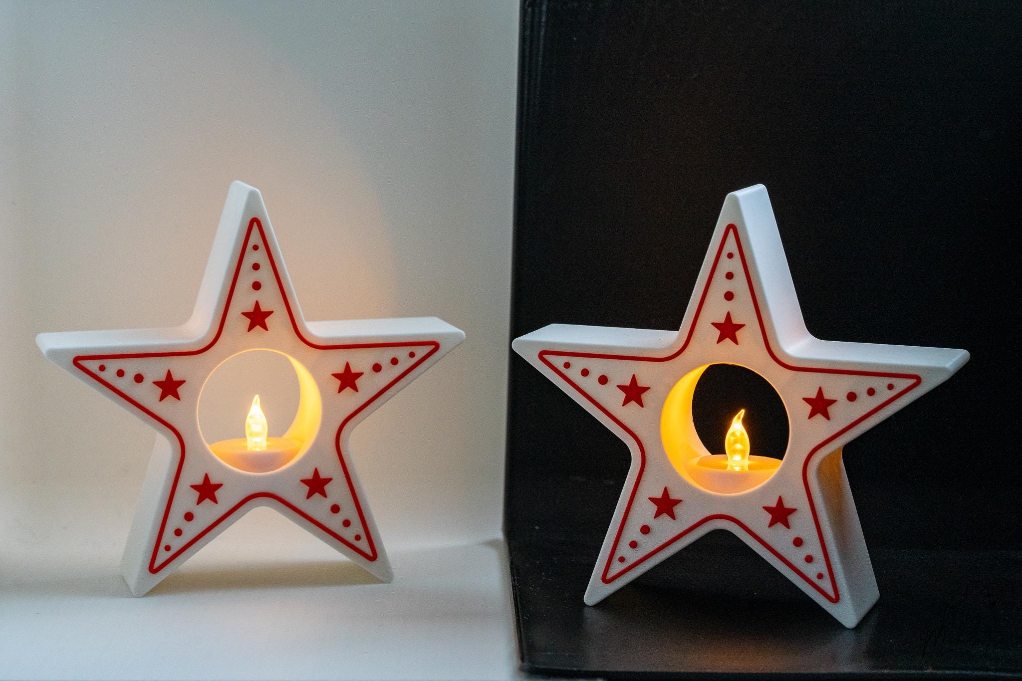 Star-shaped candle holders with red star patterns on a white and black background.