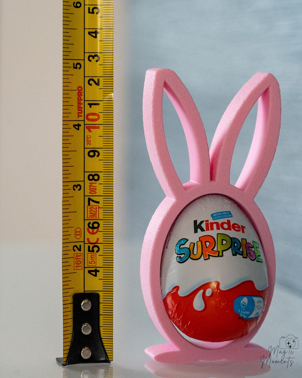 Pink bunny-shaped holder with a Kinder Surprise egg, next to a ruler for scale.
