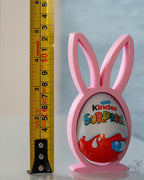 Pink bunny-shaped holder with a Kinder Surprise egg, next to a ruler for scale.