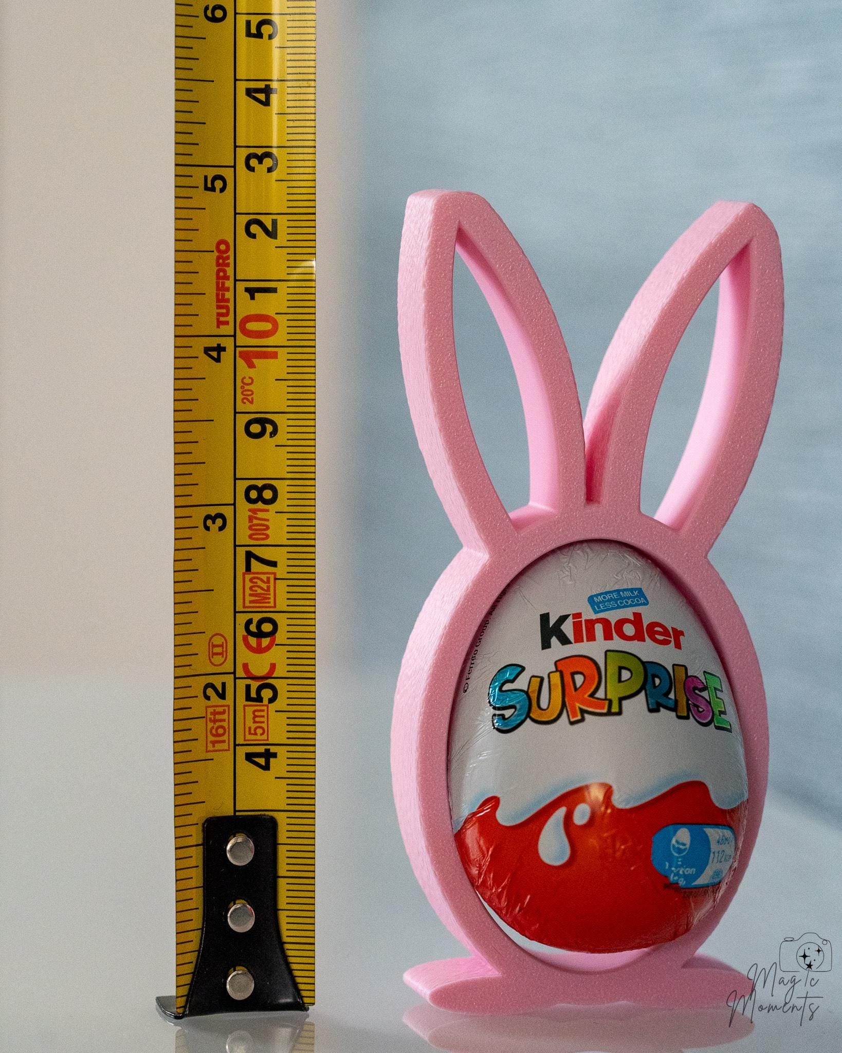 Pink bunny-shaped holder with a Kinder Surprise egg, next to a ruler for scale.