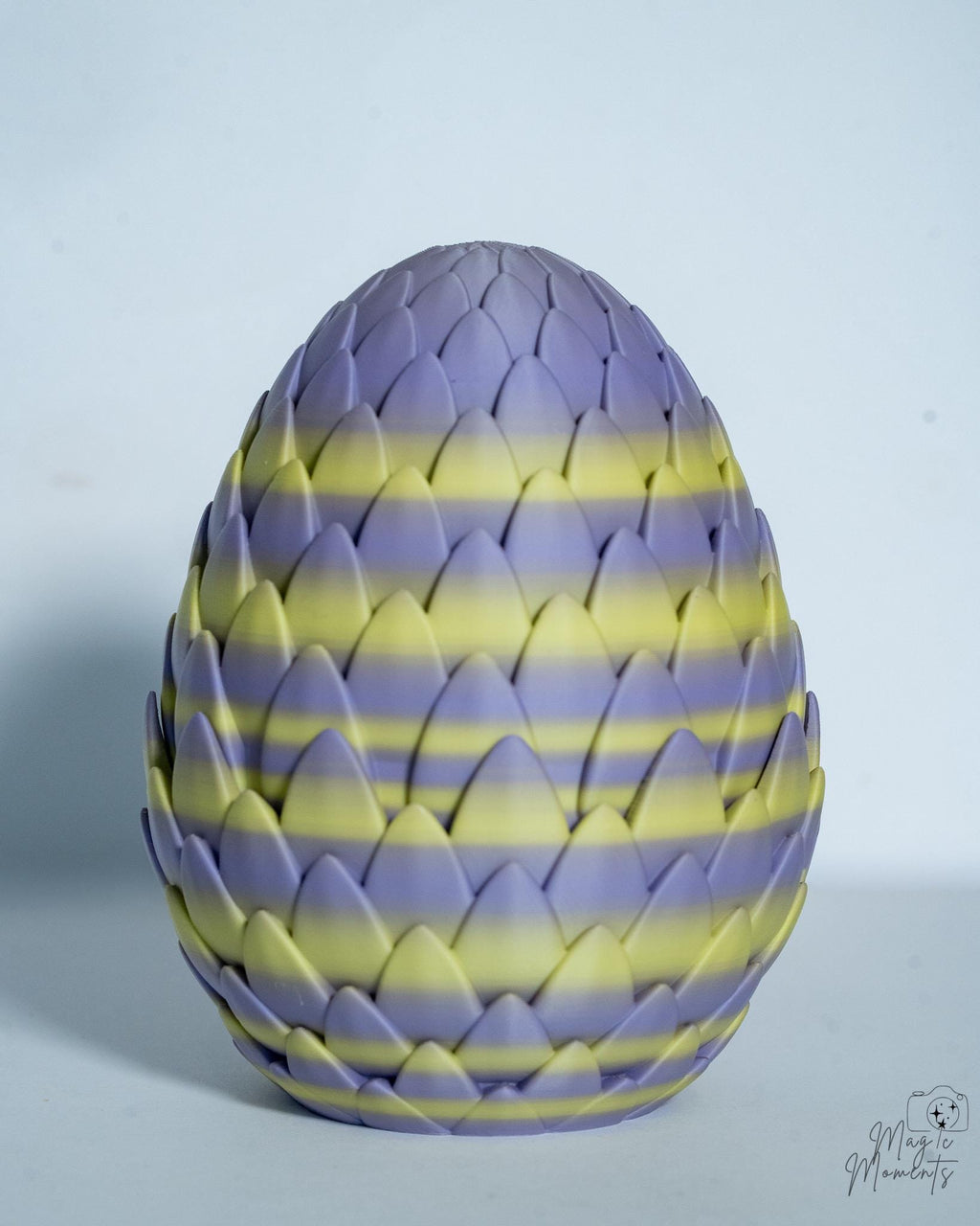 Decorative egg with purple and yellow striped pattern on a light gray background